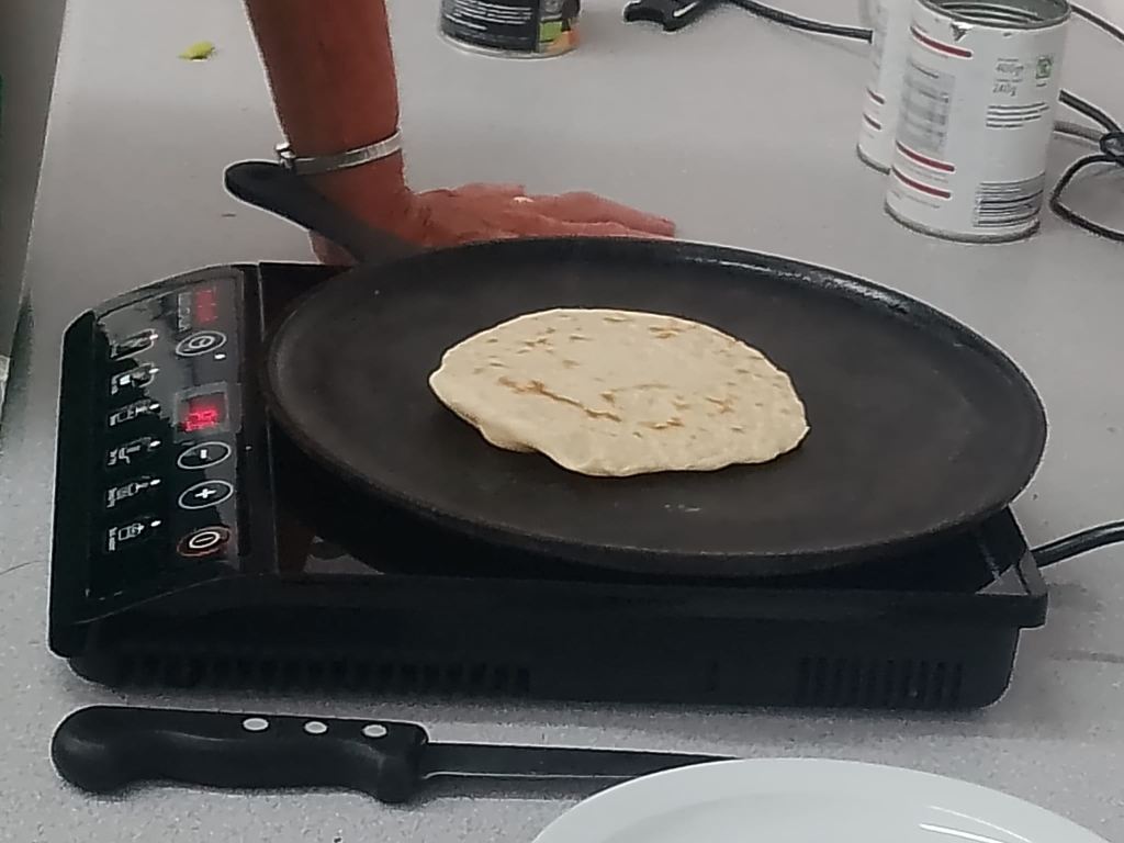 Photo of a flatbread being cooked on a pan on a portable induction hob